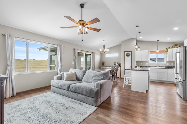living area with recessed lighting, lofted ceiling, wood finished floors, and ceiling fan with notable chandelier