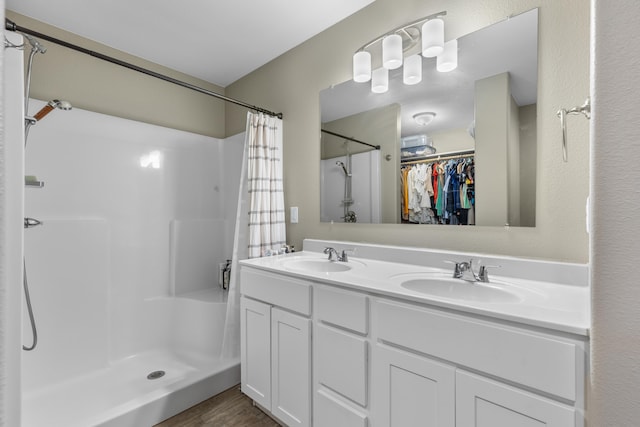 bathroom with a sink, a shower stall, and double vanity