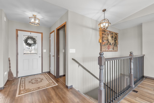 foyer entrance featuring an inviting chandelier, wood finished floors, and baseboards