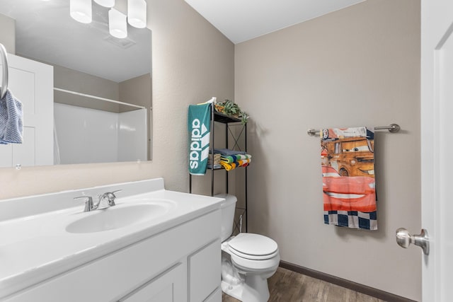 bathroom featuring toilet, visible vents, wood finished floors, a shower, and vanity