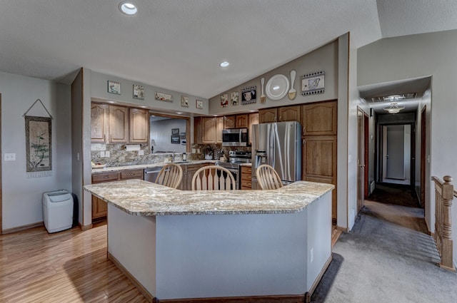 5341 Scrub Oak Cir, Rapid City, SD 57702 - kitchen with vaulted ceiling, brown cabinetry, stainless steel appliances, backsplash, and a kitchen island