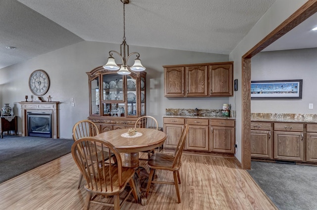 5341 Scrub Oak Cir, Rapid City, SD 57702 - dining room with lofted ceiling, light carpet, light wood-type flooring, a glass covered fireplace, and a textured ceiling