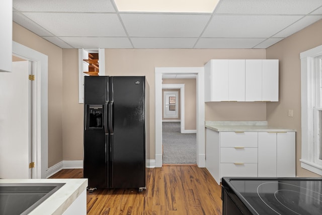 kitchen with light countertops, black appliances, white cabinetry, modern cabinets, and a paneled ceiling