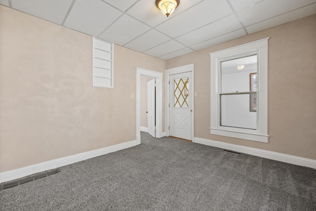 carpeted empty room featuring visible vents, a paneled ceiling, and baseboards
