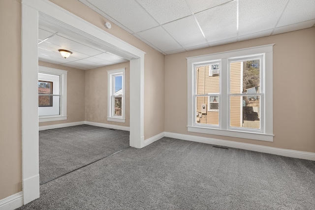 empty room with carpet, a wealth of natural light, a paneled ceiling, and baseboards