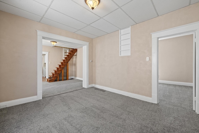 finished below grade area with stairway, a drop ceiling, carpet flooring, and baseboards