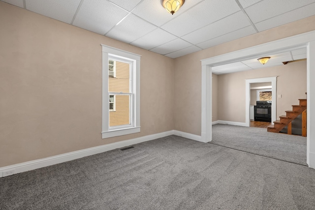 carpeted spare room featuring a paneled ceiling, stairway, a wealth of natural light, visible vents, and baseboards
