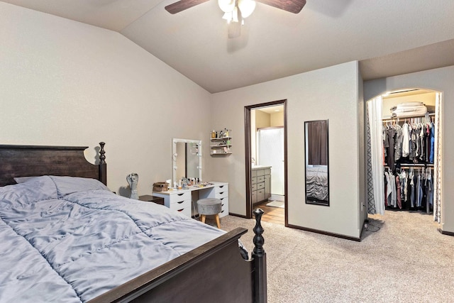 bedroom featuring arched walkways, light colored carpet, baseboards, a spacious closet, and lofted ceiling