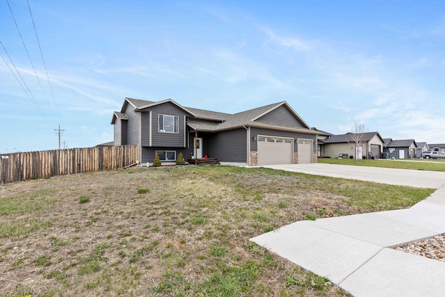 tri-level home featuring fence, a front yard, concrete driveway, and an attached garage