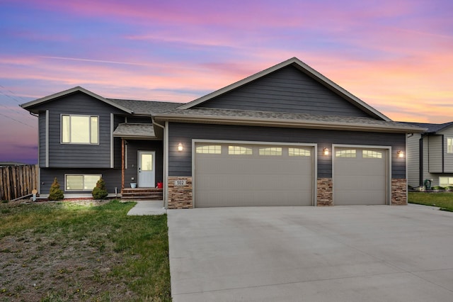 view of front of house featuring stone siding, concrete driveway, a front yard, and a garage