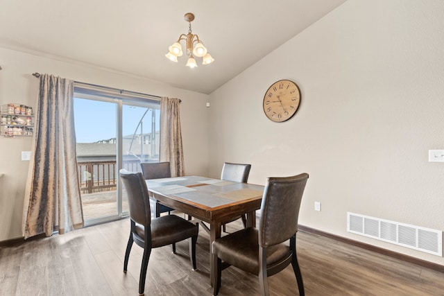 dining area with lofted ceiling, wood finished floors, a chandelier, and visible vents