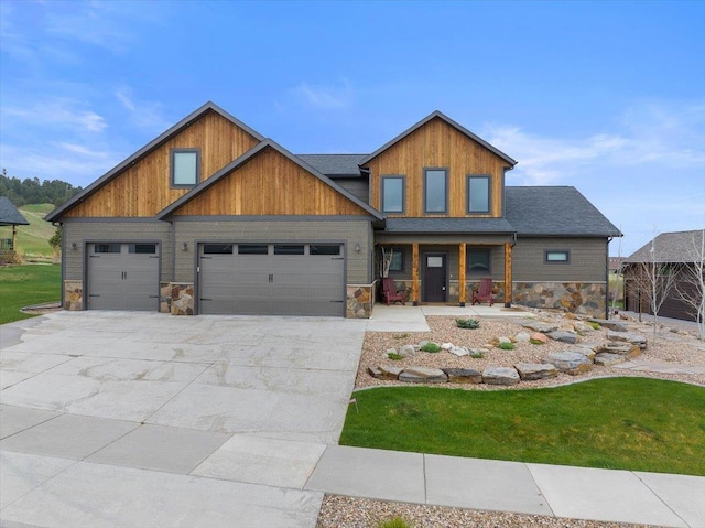 craftsman-style house with a porch, driveway, an attached garage, and stone siding