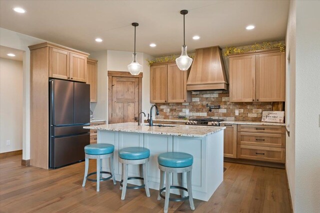 kitchen featuring dark wood-style floors, a sink, custom exhaust hood, backsplash, and freestanding refrigerator