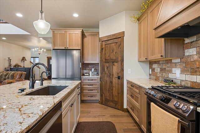 kitchen featuring decorative backsplash, light brown cabinetry, custom range hood, appliances with stainless steel finishes, and a sink