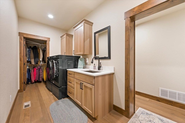 washroom with light wood-style floors, visible vents, cabinet space, and a sink