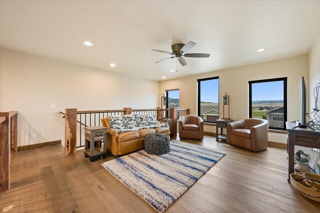 living room with ceiling fan, wood finished floors, and plenty of natural light