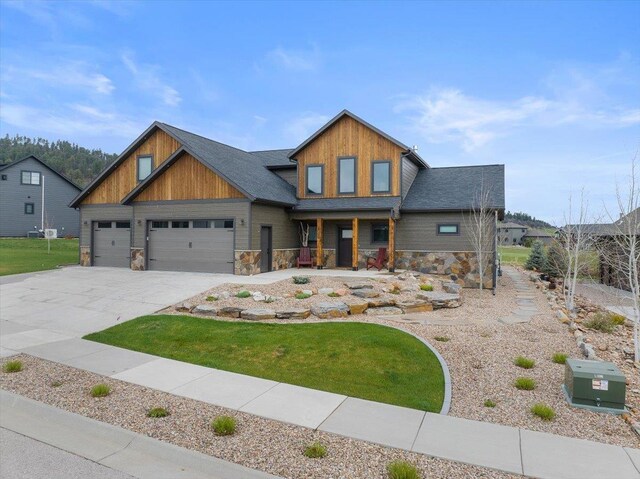 craftsman-style house with a front yard, driveway, stone siding, and an attached garage