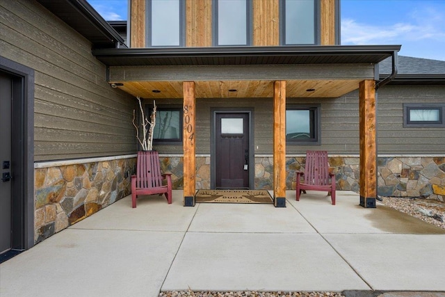 entrance to property featuring a patio and stone siding