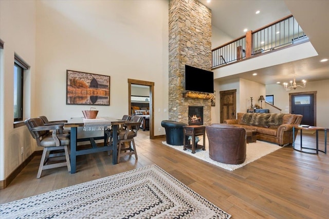 living area featuring hardwood / wood-style flooring, a notable chandelier, a high ceiling, and a fireplace