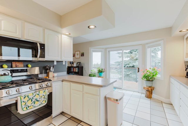 kitchen featuring light countertops, white cabinetry, stainless steel range with gas stovetop, a peninsula, and light tile patterned flooring
