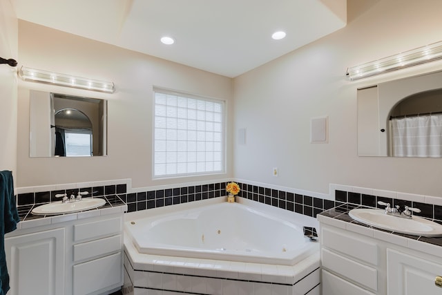 full bathroom featuring recessed lighting, two vanities, a whirlpool tub, and a sink