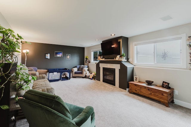 living room featuring a tiled fireplace, visible vents, and carpet flooring