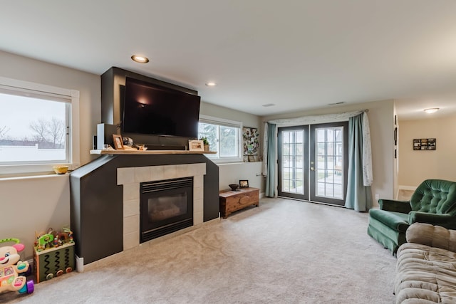 carpeted living area featuring a tiled fireplace, recessed lighting, and french doors