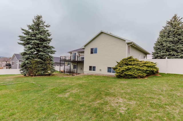 rear view of house with fence, a yard, and a wooden deck