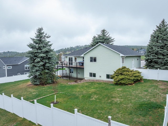 back of house featuring roof with shingles, a fenced backyard, a wooden deck, and a lawn
