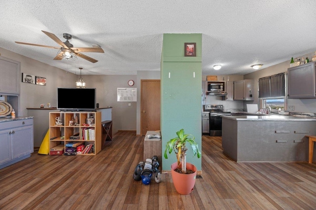 kitchen featuring a textured ceiling, a ceiling fan, appliances with stainless steel finishes, and wood finished floors