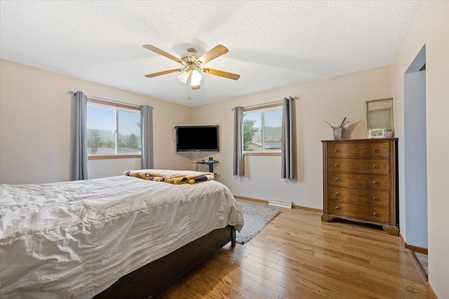bedroom featuring a textured ceiling, visible vents, multiple windows, and wood finished floors