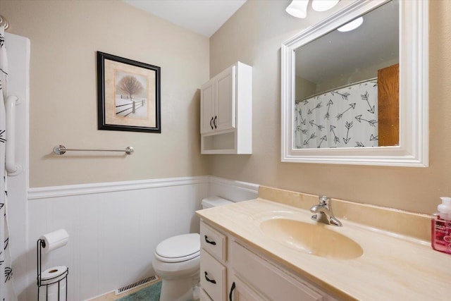 bathroom featuring visible vents, vanity, wainscoting, toilet, and a shower with shower curtain