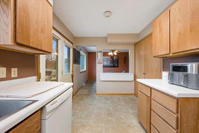 kitchen featuring white dishwasher, ceiling fan, a sink, light countertops, and baseboards
