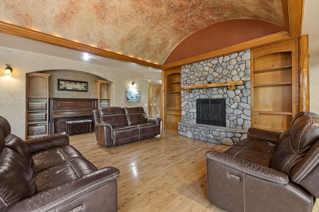 25189 Steckelberg Valley Rd, Custer, SD 57730 - living room featuring wood-type flooring, a textured wall, lofted ceiling, a stone fireplace, and built in shelves