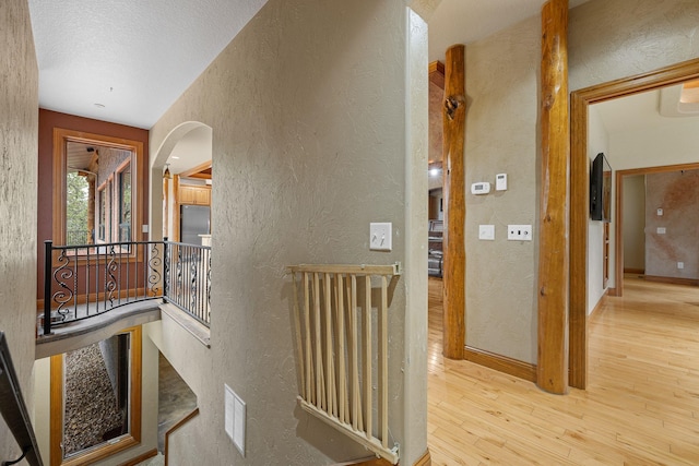 25189 Steckelberg Valley Rd, Custer, SD 57730 - hall with wood-type flooring, a textured wall, a textured ceiling, arched walkways, and an upstairs landing