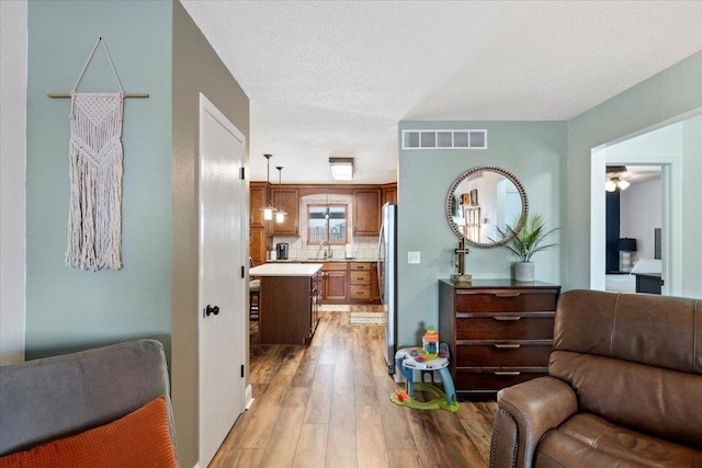 902 Yuma St, Belle Fourche, SD 57717 - living area featuring visible vents, a ceiling fan, light wood finished floors, and a textured ceiling