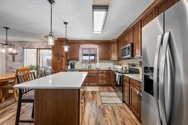 902 Yuma St, Belle Fourche, SD 57717 - kitchen featuring light countertops, appliances with stainless steel finishes, a kitchen breakfast bar, and a textured ceiling