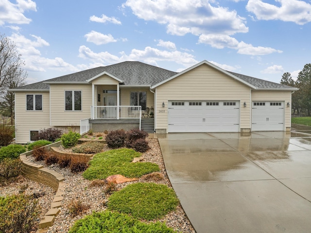 single story home featuring an attached garage, a shingled roof, covered porch, and concrete driveway