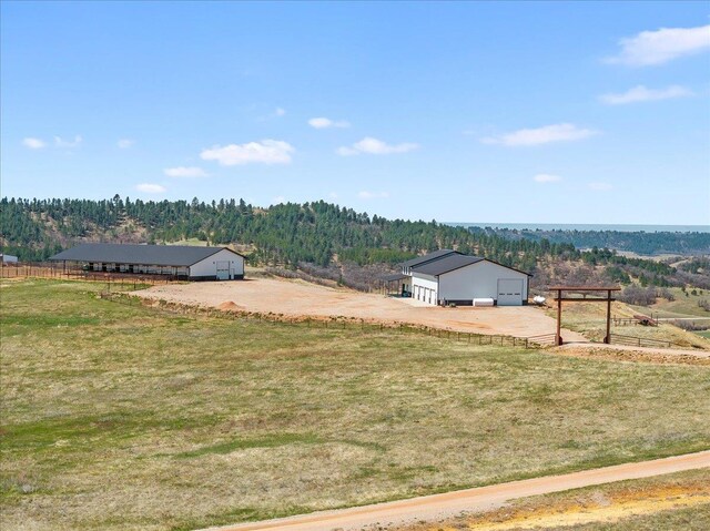 view of yard with an outdoor structure, fence, a rural view, an outbuilding, and a forest view