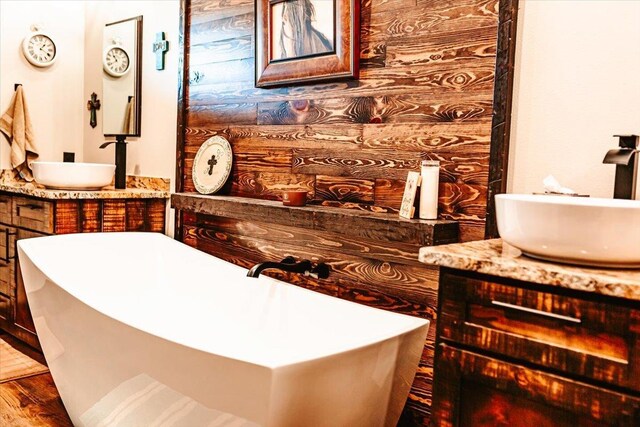 full bath featuring vanity, a freestanding tub, and wood finished floors