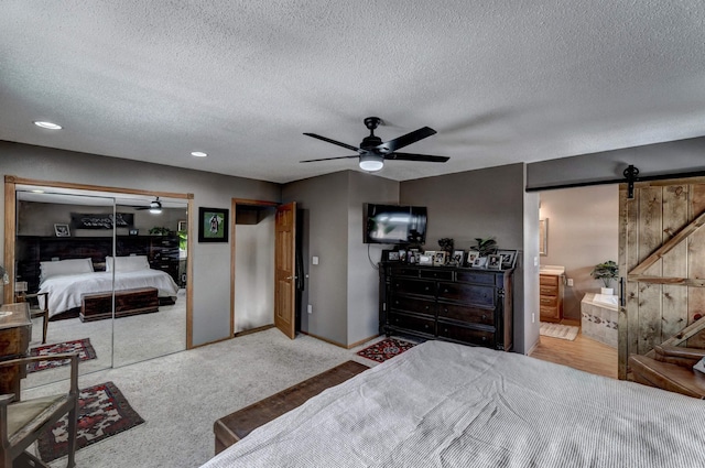 239 Deer Path, Lead, SD 57754 - bedroom featuring baseboards, a barn door, a textured ceiling, and carpet