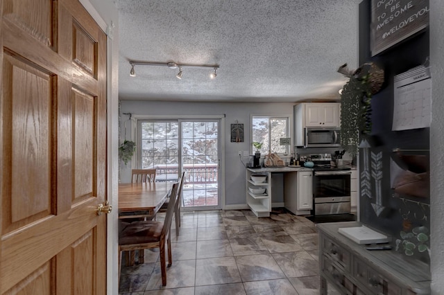 239 Deer Path, Lead, SD 57754 - kitchen featuring a textured ceiling, baseboards, stainless steel appliances, and white cabinetry