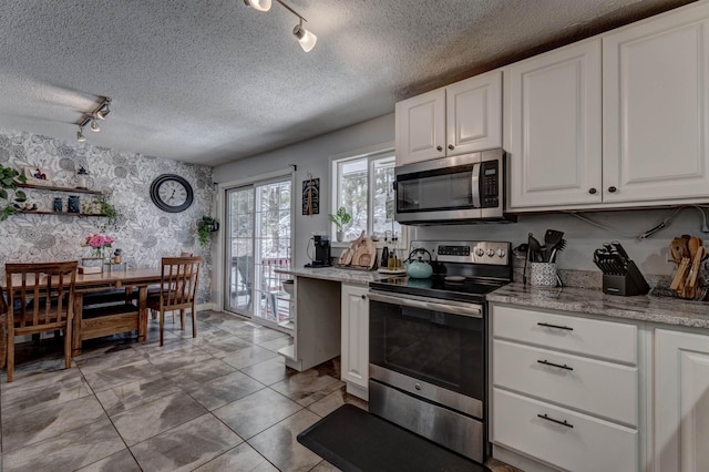 239 Deer Path, Lead, SD 57754 - kitchen with a textured ceiling, appliances with stainless steel finishes, rail lighting, white cabinets, and wallpapered walls