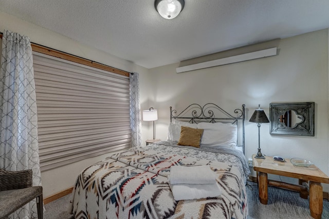 carpeted bedroom featuring baseboards and a textured ceiling