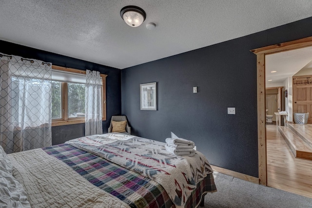 bedroom with a textured ceiling and wood finished floors