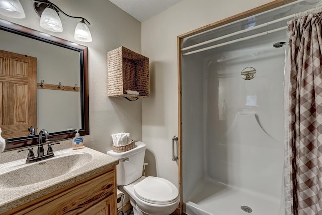 bathroom featuring vanity, a textured wall, toilet, and a shower stall