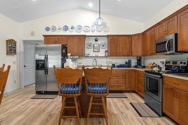 971 Northridge Dr, Rapid City, SD 57701 - kitchen featuring a kitchen breakfast bar, brown cabinetry, pendant lighting, appliances with stainless steel finishes, and light wood finished floors