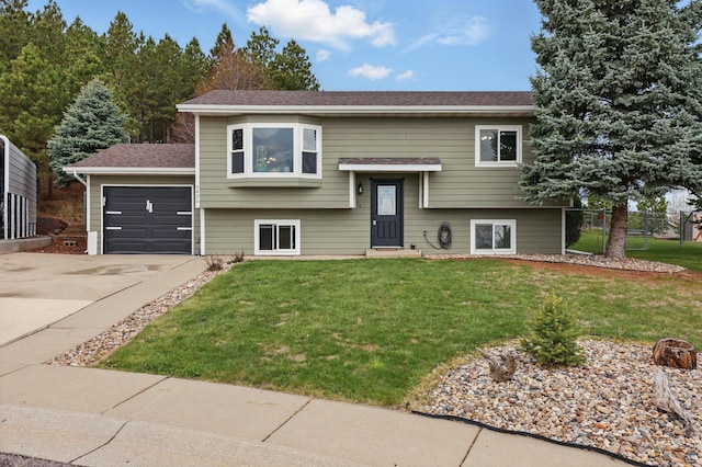 raised ranch with fence, concrete driveway, a front lawn, and a garage