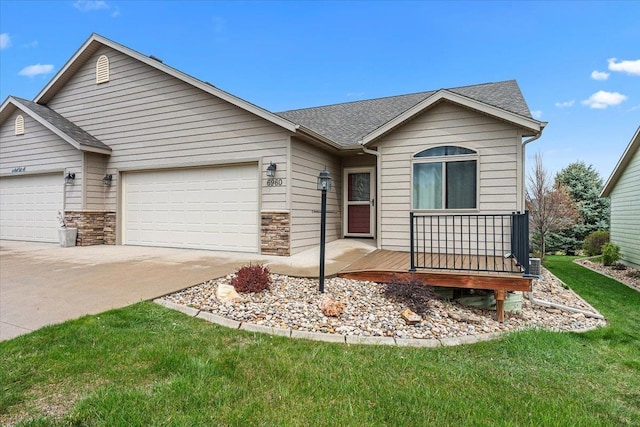 ranch-style house featuring an attached garage, a shingled roof, a front lawn, and driveway