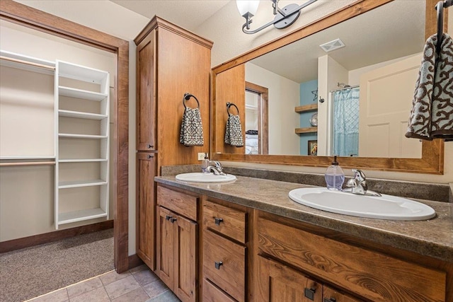 bathroom featuring a sink, double vanity, visible vents, and tile patterned floors